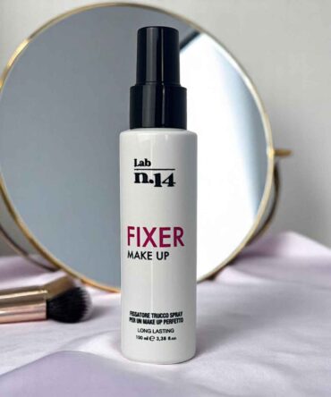 Spray fissante trucco Lab N14 da 100 ml su fondo rosa con specchio e pennello make-up