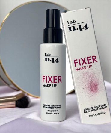 Spray fissante trucco Lab N14 da 100 ml su fondo rosa con specchio e pennello make-up